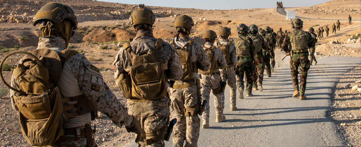 Soldiers wearing camouflage march down a desert road