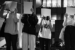 Four protestors holding blank papers covering their faces