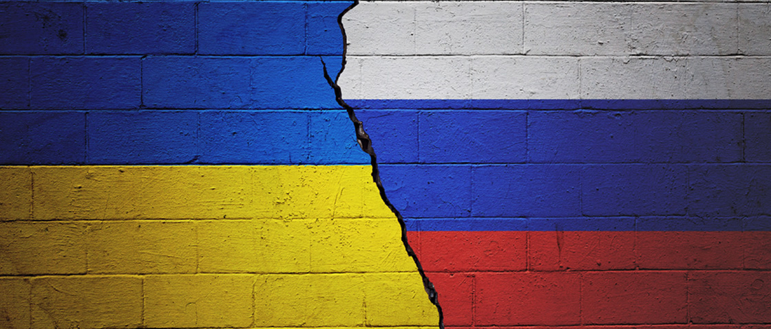 Ukraine and Russian flags on a cracked brick wall