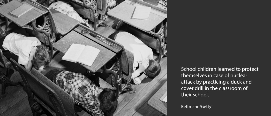 School children learned to protect themselves in case of nuclear attack by practicing a duck and cover drill in the classroom of their school.