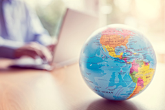 Globe on a table, with someone on a laptop in the background